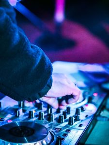 Close-up of a DJ adjusting controls on a mixer during a lively night event.