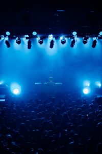 Energetic concert atmosphere with a crowd under dynamic blue stage lights. Perfect for music and event themes.