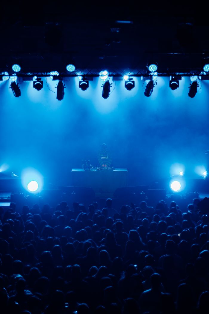 Energetic concert atmosphere with a crowd under dynamic blue stage lights. Perfect for music and event themes.